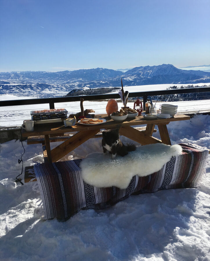 Picnic table in the snow with sheepskins and mountains