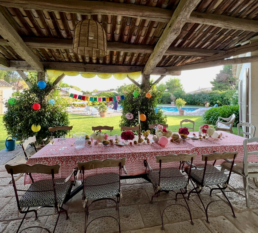 Birthday table under a stone pergola on Île de Ré, red block print, paper lanterns